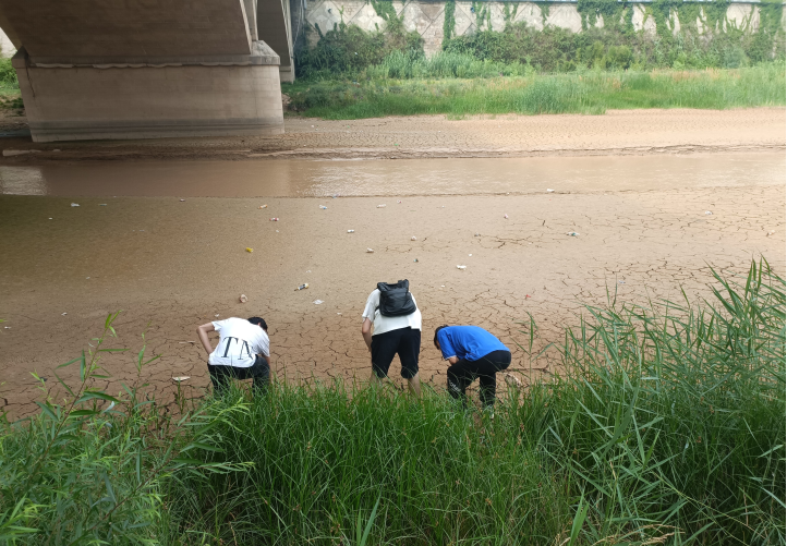 图为团队成员在河边捡拾垃圾 陈翔供图.jpg副本